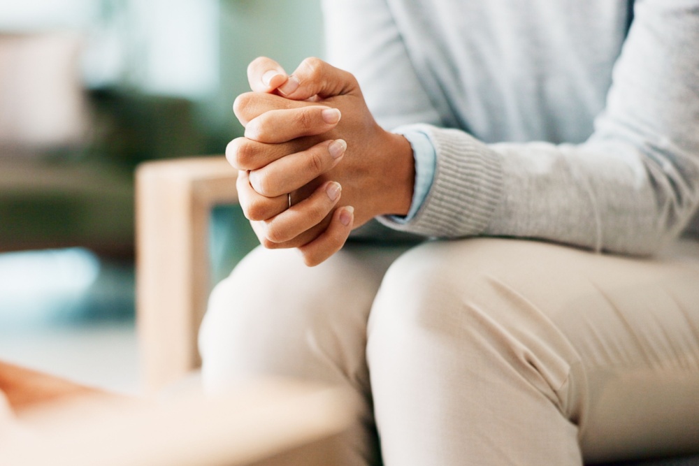 A woman sitting with her hands clasped.
