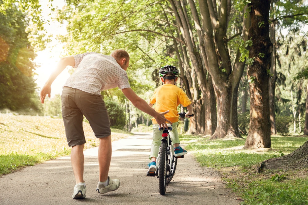 A father teaching a child to ride a bike.